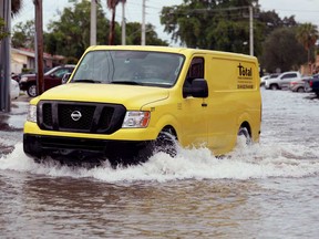 A vehicle drives through a flooded street on June 13, 2024, in Hallandale Beach, Fla.