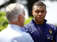 French soccer player Kylian Mbappe, right, listening to head coach Didier Deschamps at the national soccer team training center in Clairefontaine.