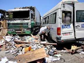 A Palestinian man checks the underside of a damaged van