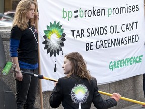 Greenpeace activists, some dressed in business suits and wearing smoke stack hats, 'greenwash' BP's Calgary headquarters with large letters spelling out 'TAR SANDS' in Calgary, Thursday, April 15, 2010.