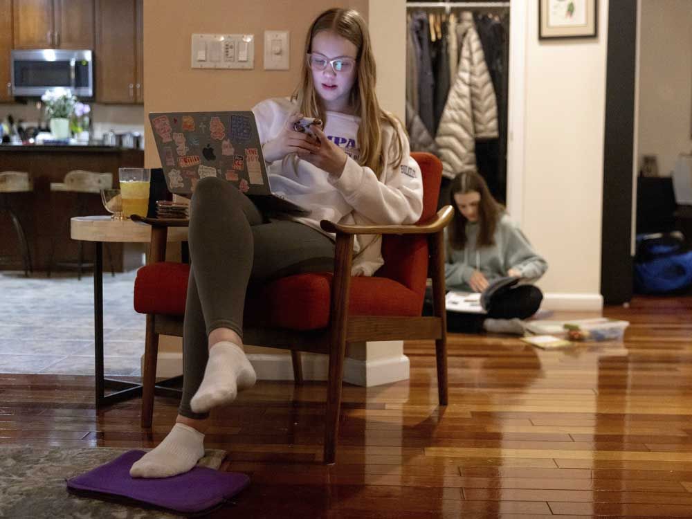Kate Bulkeley uses her phone to print textbook pages while Sutton packs art materials ahead of a ski vacation, Friday, Feb. 16, 2024, in Westport, Conn.