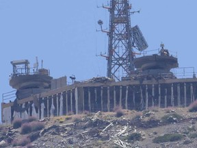Uma posição militar israelense danificada, alvejada por combatentes do Hezbollah, é vista no topo do Monte Hermon, nas Colinas de Golã controladas por Israel, onde as fronteiras entre Israel, Síria e Líbano se encontram. É vista de Chebaa, uma cidade libanesa perto da fronteira com Israel, sul do Líbano, em 26 de junho de 2024.
