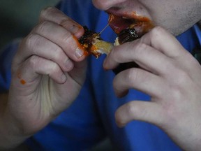 A man eats a chicken wing, Wednesday, June 12, 2024, at a barbecue restaurant in Cincinnati.