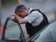 Almost 10 years after a disturbed man with a rifle killed three Mounties in Moncton, N.B., the RCMP have yet to fully implement a key recommendation from a 2014 review aimed at preventing such deadly encounters. An RCMP officer rests his head at a roadblock in Moncton, N.B. on Thursday, June 5, 2014.