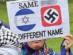 A counter-protester holds up a sign with a swastika on it.