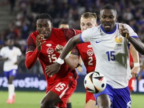 France's Marcus Thuram, right, duels for the ball with Canada's Alistair Johnston, centre, and Moise Bombito during the international friendly soccer match between France and Canada at the Matmut Atlantique stadium in Bordeaux, southwestern France, Sunday, June 9, 2024. Canada has moved up one place to No. 48 in the latest FIFA men's world rankings.
