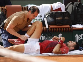 FILE - Serbia's Novak Djokovic receives medical assistance for his right knee during his fourth round match of the French Open tennis tournament against Argentina's Francisco Cerundolo at the Roland Garros stadium in Paris, Monday, June 3, 2024. Novak Djokovic withdrew from the French Open with an injured right knee on Tuesday, June 4, 2024, ending his title defense and meaning he will relinquish the No. 1 ranking.