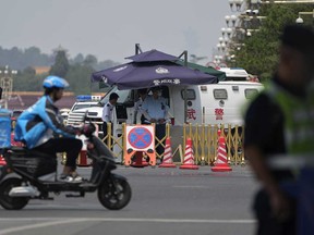 Securities stand watch near police vehicles parked at a traffic junction road near Tiananmen Square in Beijing, Tuesday, June 4, 2024.