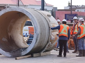 City of Calgary workers inspect the damaged water main pipe after it was removed at the repair site in Montgomery on Monday, June 10, 2024.