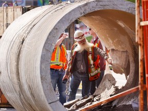 City of Calgary workers inspect the damaged water main pipe after it was removed at the repair site in Montgomery on Monday June 10, 2024.