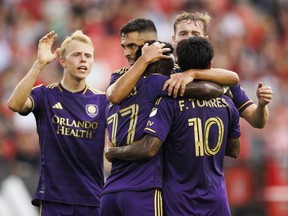 Orlando City SC midfielder Martin Ojeda (second left) embraces forward Ivan Angulo (77) and forward Facundo Torres (10) after scoring the first goal against Toronto FC during the first half of their MLS soccer match in Toronto, Wednesday, July 3, 2024.