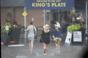 All dressed up with nowhere to go. Spectators seek cover as rain washes away the King’s Plate at Woodbine on Saturday, Aug. 17, 2024. MICHAEL BURNS PHOTO