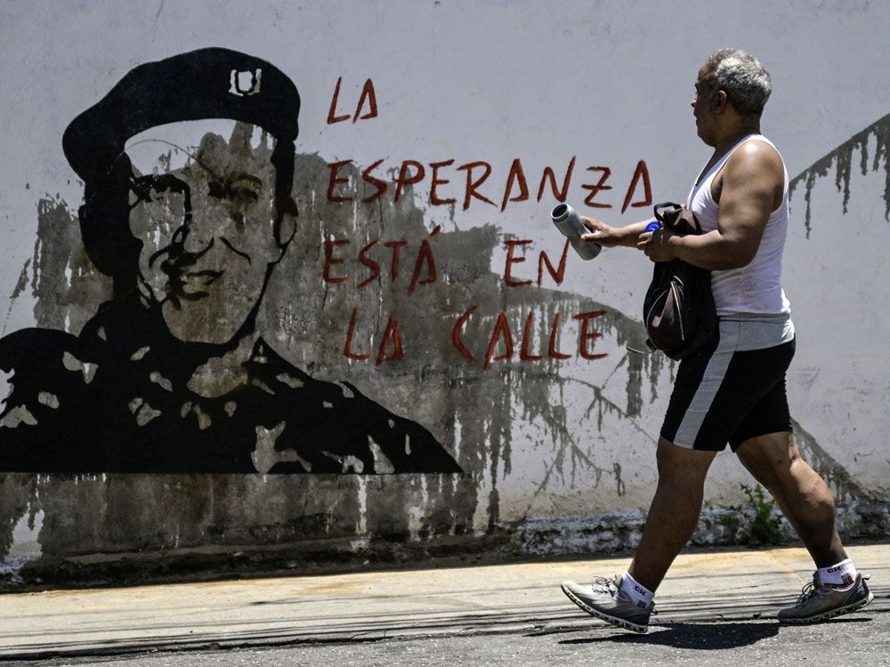 Un hombre camina frente al graffiti del expresidente venezolano Hugo Chávez en el barrio de Petare en Caracas el 1 de agosto de 2024. 
