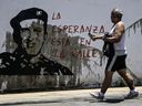 Un hombre camina frente al graffiti del expresidente venezolano Hugo Chávez en el barrio de Petare en Caracas el 1 de agosto de 2024.