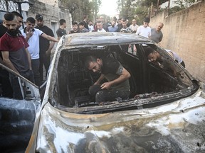 La gente revisa un auto quemado