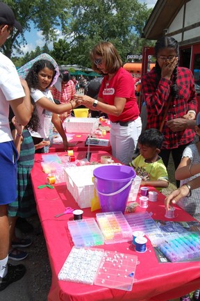 Los niños usan cuentas para hacer una etiqueta para una bolsa en el evento Let Your Imagination Run Wild en el Zoológico de Toronto el sábado 10 de agosto de 2024.