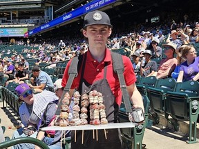 A vendor carries strawberry kebabs at Coors Field
