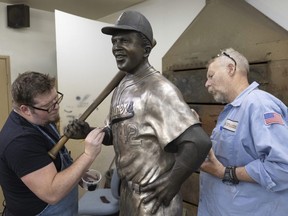 Nate Ford (left) and Jeff Herndon apply finishing touches to a statue of Baseball Hall of Fame member and civil rights pioneer Jackie Robinson at Art Castings of Colorado in Loveland, Colo., on July 24, 2024.