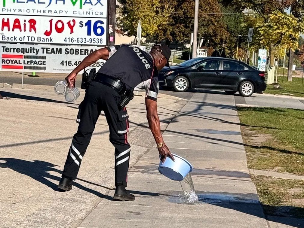 A police officer cleans up a Swastika left on the sidewalk on Bathurst Street at Sheppard Avenue Sunday. Police say before they removed it they took pictures and forensics and are investigating -- 
