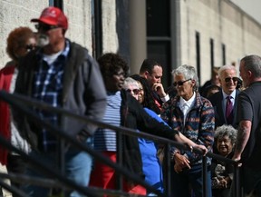 US President Joe Biden (R) waits in line with voters outside a polling station in New Castle, Delaware, October 28, 2024.