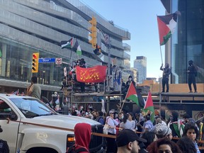 Protesters demonstrate and wave flags at Yonge St. and Bloor St. in downtown Toronto, Saturday, Oct. 5, 2024.