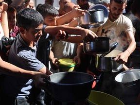 Displaced Palestinians queue to receive food rations, offered by a charity, in Gaza's Al-Shati refugee camp on Oct. 17, 2024, amid the ongoing war between Israel and the Palestinian militant group Hamas in the besieged Palestinian territory.