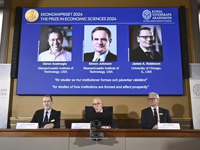 El secretario permanente de la Academia de Ciencias, Hans Ellegren (centro), Jakob Svensson, izquierda, y Jan Teorell, de la Asamblea Nobel, anuncian el premio Nobel de Economía en memoria de los ganadores, Daron Acemoglu, Simon Johnson y James A. Robinson, vistos en la pantalla, durante una reunión de prensa. en la Real Academia Sueca de Ciencias en Estocolmo, Suecia, el lunes 14 de octubre de 2024.