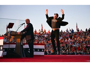 (FILES) Tesla CEO Elon Musk (R) jumps on stage as he joins then-Republican presidential candidate Donald Trump during a campaign rally at site of his first assassination attempt in Butler, Penn., on Oct. 5, 2024. (Photo by Jim WATSON / AFP)