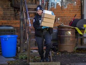A police officer leaves a building with boxes.