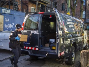 A police officer leaves a building with boxes.