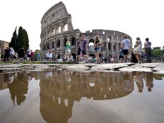 Tourists walk by the ancient Roman Colosseum