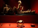 Jewelry found in the ruins of a house in Pompeii are displayed, backdropped by the casts of two adults and two children who died together in the house in Pompeii, at the exhibition,