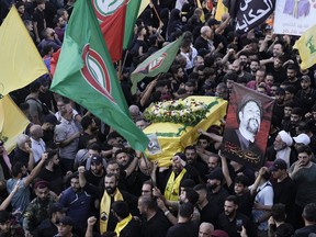 Hezbollah fighters carry a coffin.