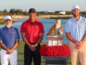 Scottie Scheffler of the United States, right, poses with the trophy and Dr. Pawan Munjal, Executive Chairman of Hero MotoCorp, left, and Tiger Woods of the United States after winning the final round of the Hero World Challenge 2024 at Albany Golf Course on Dec. 8, 2024 in Nassau, Bahamas.