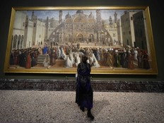 A visitor watches the painting 'St.Mark preaching in Alexandria' by Gentile and Giovanni Bellini, at the Pinacoteca Brera museum, in Milan, Italy, Wednesday, Dec. 4, 2024.