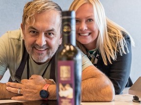El chef Dario Tomseli y la estratega de la vida Anita Hydema sonriendo detrás de una botella de aceite de oliva.