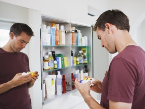 La medicina del hombre mira botellas de gabinetes.