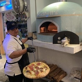 A worker pulls a pizza out of the firewood-burning stove at Clarabell’s in Hamilton, Bermuda. (Jane Stevenson/Toronto Sun)