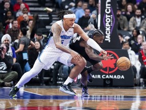 El delantero del Orlando Magic, Paolo Banchero, y el base de los Toronto Raptors, Jamal Shead, luchan por la posesión del balón en Toronto el martes por la noche. Thomas Skrlj/Prensa canadiense