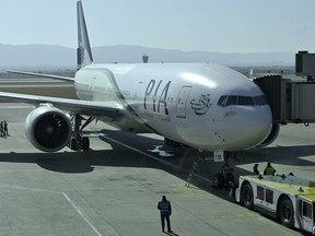 Ground staff work beside the state-run Pakistan International Airlines plane preparing to take-off for Paris after the airline resumes direct flights to Europe after EU lifted a four-year ban, at the Islamabad International Airport, in Islamabad, Pakistan, Friday, Jan. 10, 2025.
