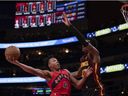 El delantero de los Toronto Raptors, Scotty Burns (4), dispara el balón frente a los Atlanta Hawks, Onyeka Okongwu (117), durante la primera mitad de un partido de baloncesto de la NBA, el jueves 23 de enero de 2025, en Atlanta.