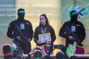 Hamas militants escort Israeli hostage Agam Berger (C) on a stage before handing her over to a Red Cross team in Jabalia on January 30, 2025, as part of their third hostage-prisoner exchange. (Photo by OMAR AL-QATTAA/AFP via Getty Images)