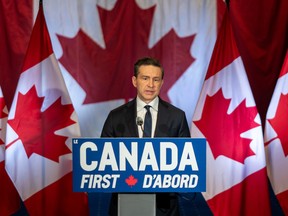 Pierre Poilievre speaking at podium with flags behind him