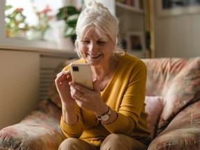 Older woman smiling while looking at her cellphone.