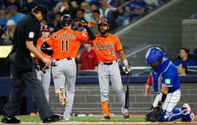 The Orioles' Jordan Westburg (11) is welcomed to the plate by teammate Cedric Mullins (31) after Westburg hit a solo home run against the Blue Jays in the first inning at Rogers Centre in Toronto, Saturday, March 29, 2025.