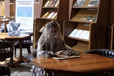 A tour guide at New Zealand's Parliament gives a spooky tour of the historical Parliament library, constructed in the late 19th century and rumored to be haunted, in Wellington, Thursday, March 20, 2025. (AP Photo/Charlotte Graham-McLay)