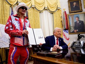 U.S. President Donald Trump, accompanied by entertainer Kid Rock, signs an executive order in the Oval Office of the White House on March 31, 2025 in Washington, D.C.