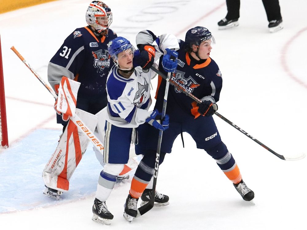 Landon McCallum, middle, of the Sudbury Wolves, and Blake Smith, of the Flint Firebirds, battle for position in front of Firebirds goalie Nathan Day during OHL action in 2023.