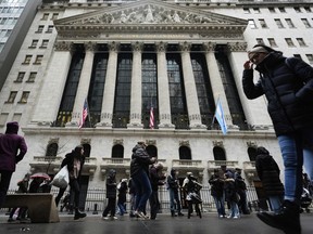 People stand in front of the New York Stock Exchange.