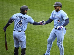 Blue Jays' Anthony Santander, right, celebrates after hitting his first home run with Toronto with George Springer, left, during the third inning of a game against the Orioles in Baltimore, Saturday, April 12, 2025.